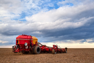 Seeding machine on the empty field at sunset