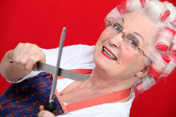 grandmother with haircurlers sharpening knives