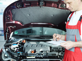 Motor mechanic in front of engine bay is checking repair details