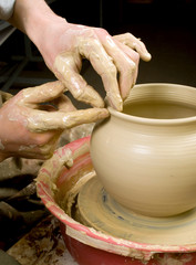 hands of a potter, creating an earthen jar of white clay