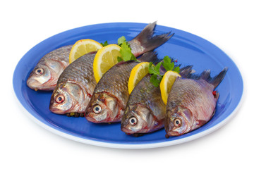 Fresh fishes with lemon and parsley on plate isolated on white