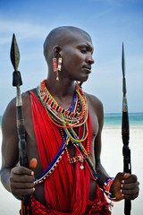 Maasai sitting by the ocean on the beach - obrazy, fototapety, plakaty