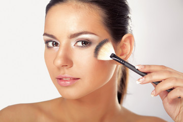 Fototapeta premium Portrait of attractive young adult woman applying blusher