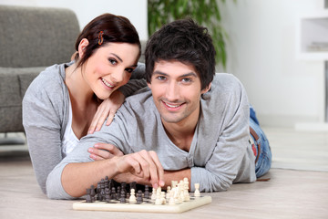 Couple laying on floor playing chess