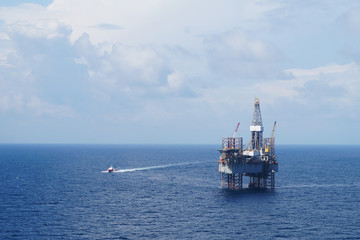 Jack up drilling rig and crew boat in the middle of the sea