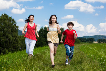 Obraz premium Active family - mother and kids running, jumping outdoor