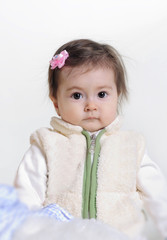 The small beautiful girl lies on a white background with toys