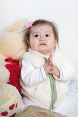 The small beautiful girl lies on a white background with toys
