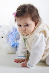 The small beautiful girl lies on a white background with toys