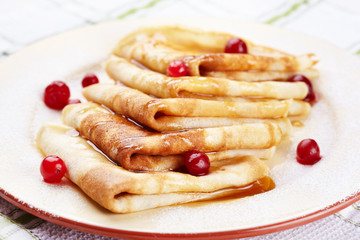 Pancakes with cranberry berries and honey on a plate