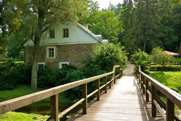 Fototapeta na wymiar Wooden bridge and an old stone house.