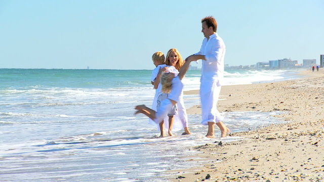 Caucasian Parents Swinging their Children on Beach