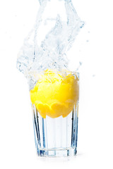 Lemon falling in glass with water