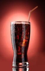 Glass of cola with ice on red background