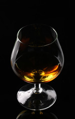 Glass of cognac on black background