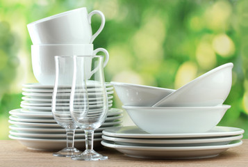 Clean dishes on wooden table on green background