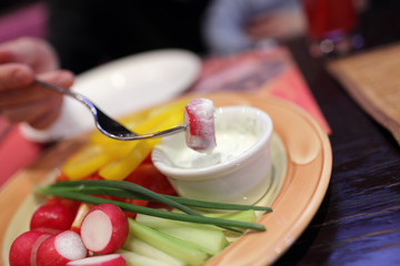 Dipping piece of radish into sauce