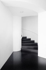 Spiral staircases between white walls and black floor