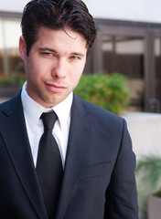Portrait of a young businessman in suit standing outdoors