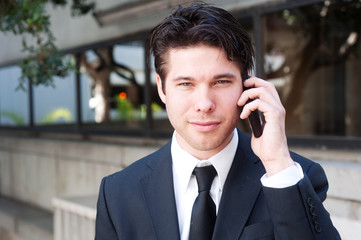 Portrait of a young business man using cell phone, smiling