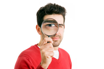 young man looking through magnifying glass, isolated on white