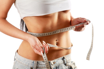 A young woman measuring her waist, focus on her belly