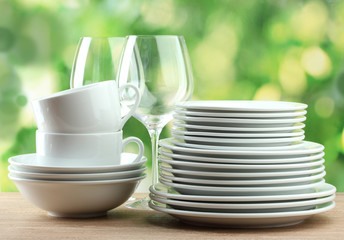 Clean dishes on wooden table on green background