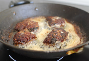 Several chops boiling oil on old frying pan
