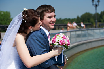 Happy bride and groom with bouquet in park