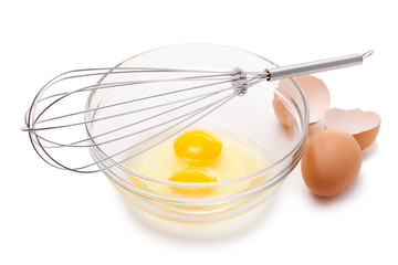 Wire whisk and brown eggs, isolated on white.