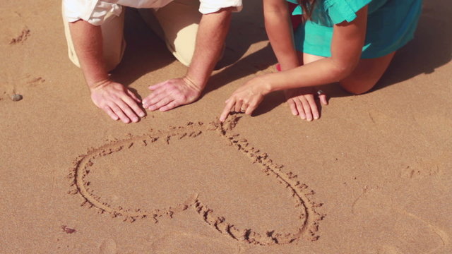 Couple drawing a heart shape in the sand