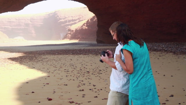 Couple looking at photos in digital DSLR camera outdoors