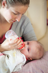 Mother feeding infant girl with a milk bottle