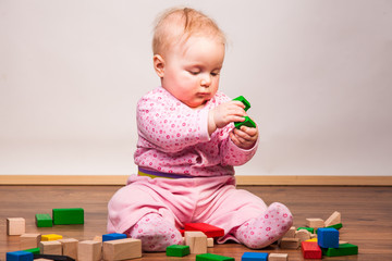Infant girl playing in room on wooden floor
