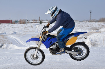 Naklejka premium Motocross, motorcycle driver flies over hill out of snow