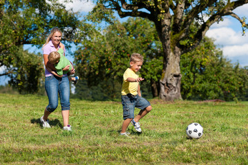 Obraz premium Glückliche Familie spielt Fußball im Sommer