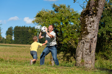 Glückliche Familie spielt Fußball im Sommer