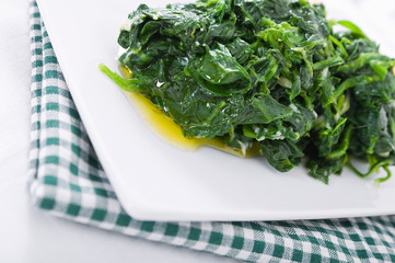 Boiled spinach on white dish. Spinaci bolliti.