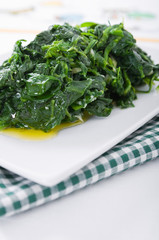 Boiled spinach on white dish. Spinaci bolliti.