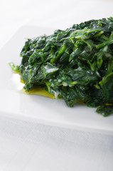 Boiled spinach on white dish. Spinaci bolliti.
