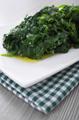 Boiled spinach on white dish. Spinaci bolliti.