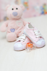 baby shoes and teddy bear toy on a wooden floor