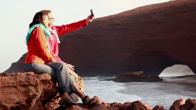 Happy couple taking photo with cellphone on Legzira beach