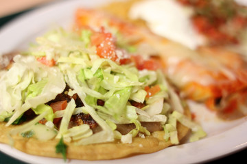 Tostada and enchilada plate with rice, beans, and salsa.