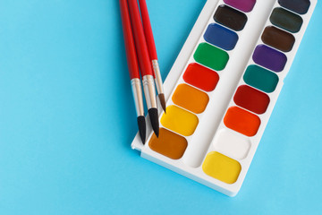 brushes for watercolors paints for children on blue background