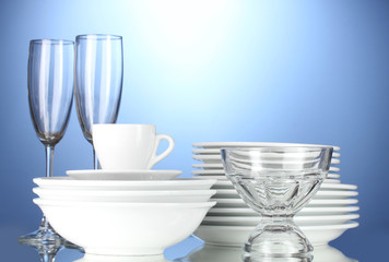 empty bowls, plates, cups and glasses on blue background