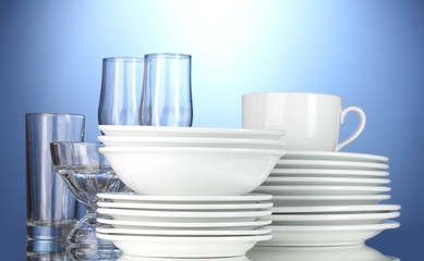 empty bowls, plates, cups and glasses on blue background