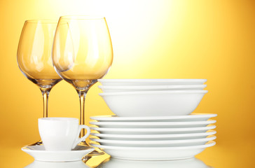 empty bowls, plates, cups and glasses on yellow background