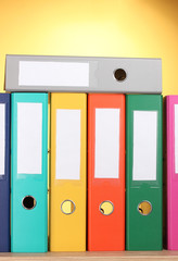 bright office folders on wooden table on yellow background