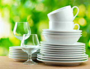 Clean dishes on wooden table on green background